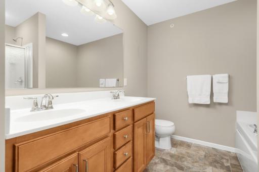 Private primary bath with dual sinks, a separate soaking tub and shower, and a linen closet for added storage and convenience.