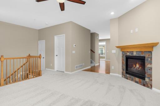 Bright and welcoming living room featuring a cozy gas-burning fireplace and neutral finishes. Nicely sized coat closet at the top of the stairs and a 1/2 bathroom.
