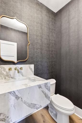 Half bath is wallpapered w/ a mitered quartz sink