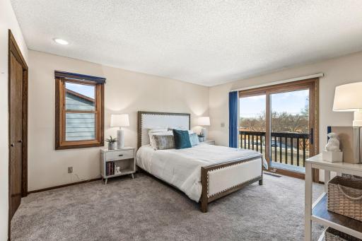 Large primary bedroom has newer carpet, window, and triple pane patio door.