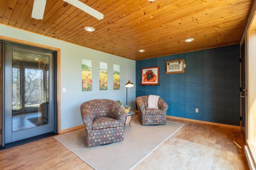 The room has a pine tongue in groove ceiling, cork floor, and wall AC unit.