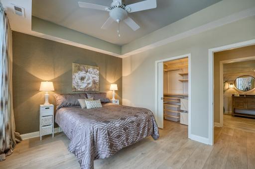 The bedroom features a custom grass-paper wall and a walk-in closet with custom shelving. Perfectly situated bedroom, closet, and bathroom.