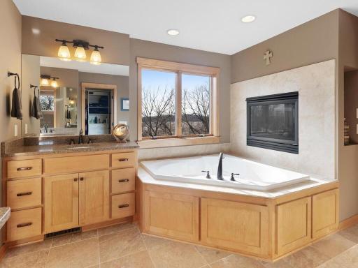 Luxury primary bath offers his-and-hers vanities with granite tops, garden whirlpool tub with fireplace, generous walk-in closet, and separate walk-in shower. What a retreat!