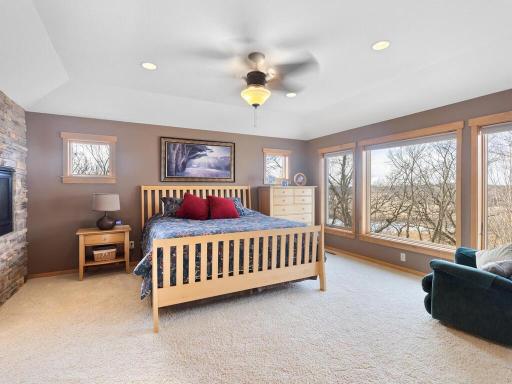Huge primary suite boasts large windows with views into the wetlands, tray vaulted ceiling with fan/light and 2-sided fireplace with stone surround.