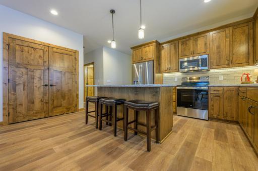 The kitchen is a true centerpiece, featuring rich stained alder cabinetry, luxurious granite countertops, a stylish tile backsplash, and a suite of stainless steel GE appliances. Storage is abundant in the 6' linear pantry.