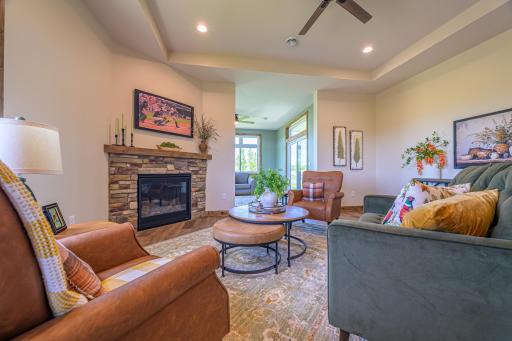 The great room boasts an elegant tray vault ceiling and a striking corner gas fireplace framed by beautiful stonework.