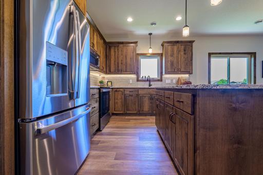 The kitchen is a true centerpiece, featuring rich stained alder cabinetry, luxurious granite countertops, a stylish tile backsplash, and a suite of stainless steel GE appliances.