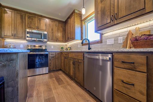 The kitchen is a true centerpiece, featuring rich stained alder cabinetry, luxurious granite countertops, a stylish tile backsplash, and a suite of stainless steel GE appliances.