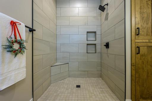 The primary bedroom features a roll-in tiled shower and a linen cabinet.