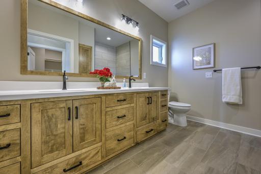 Private primary ensuite bathroom with double sinks and a roll-in shower.