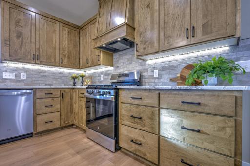 The kitchen features a commercial grade vent hood, a granite countertop, and a tile backsplash.