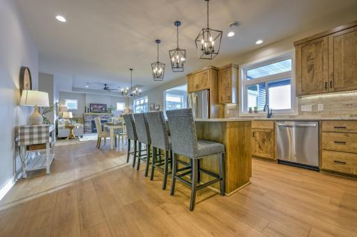 The kitchen features beautifully stained maple cabinetry and is equipped with stainless steel GE appliances, granite countertops, tile backsplash, a linear pantry, and a commercial grade vent hood.