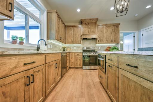 The kitchen features beautifully stained maple cabinetry and is equipped with stainless steel GE appliances. A linear pantry offers convenient storage solutions.