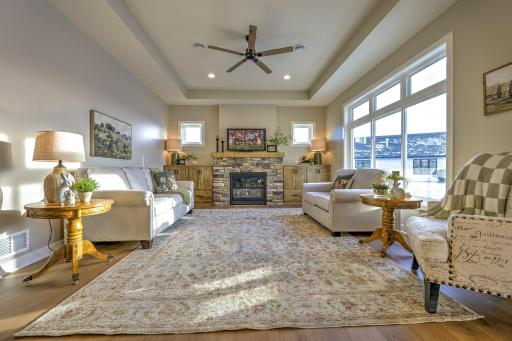 The great room is both elegant and comfortable, showcasing a tray vault ceiling and a gas fireplace surrounded by custom built-in cabinetry.