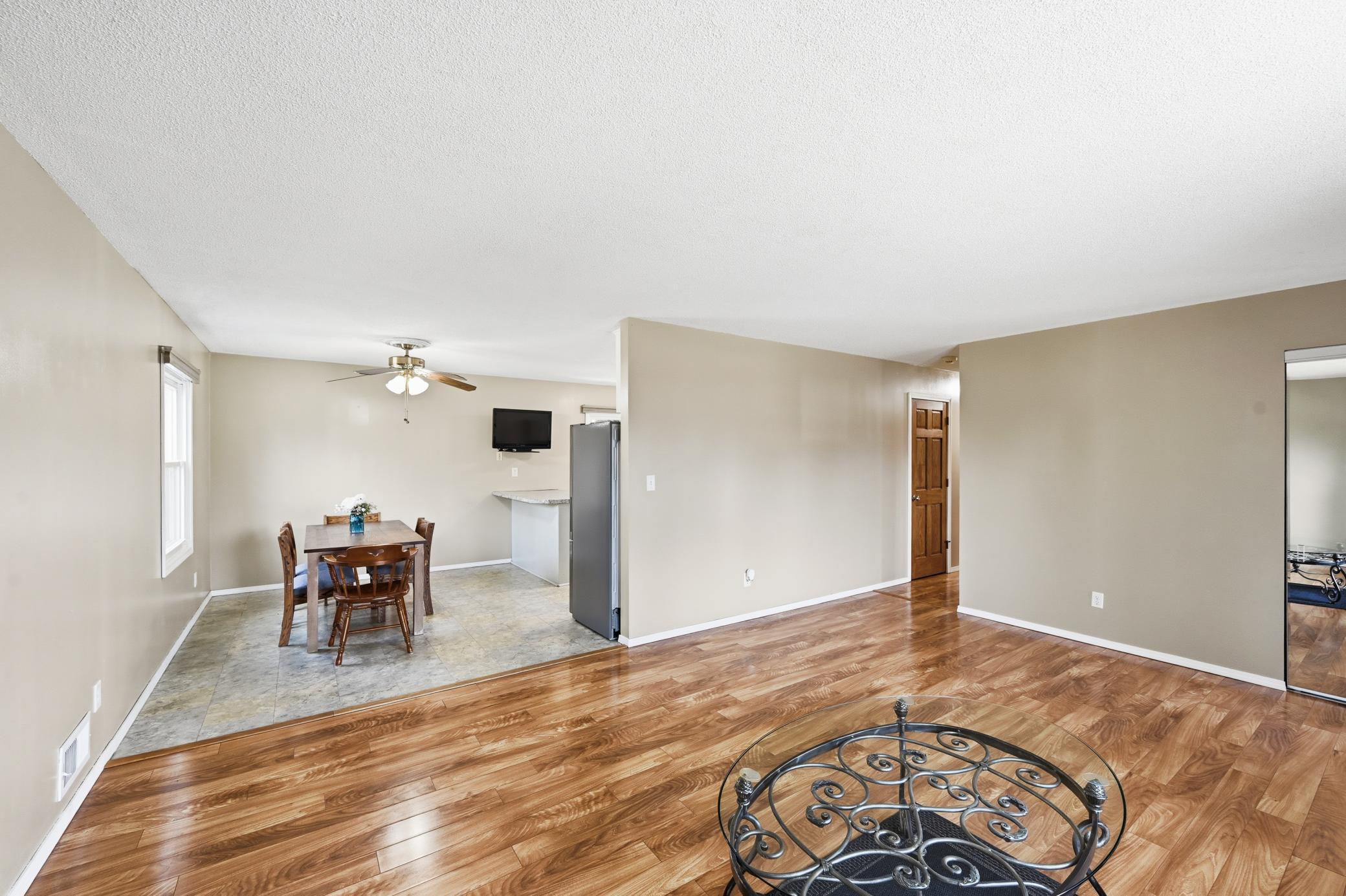 The open-concept layout seamlessly connects the dining area and kitchen to the main living space, featuring durable wood-look flooring throughout.