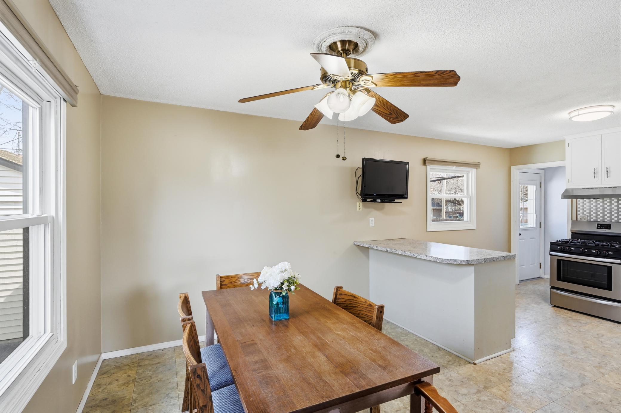 The dedicated dining area offers a cozy spot for family meals, highlighted by a classic ceiling fan and easy access to the breakfast bar.