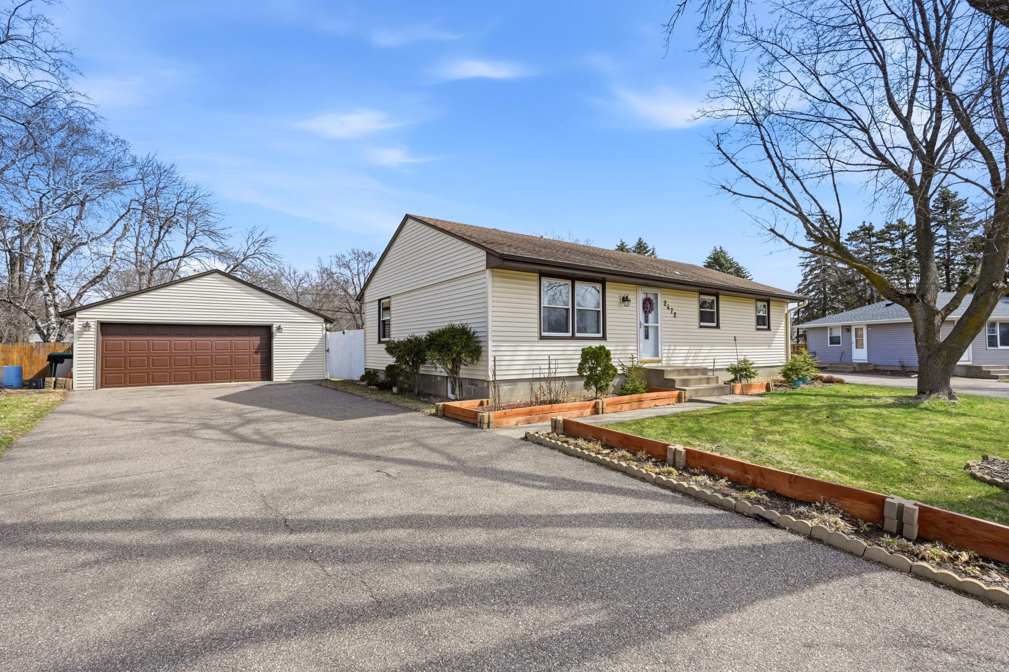 A spacious paved driveway leads to an oversized detached garage, providing ample parking and extra storage space.