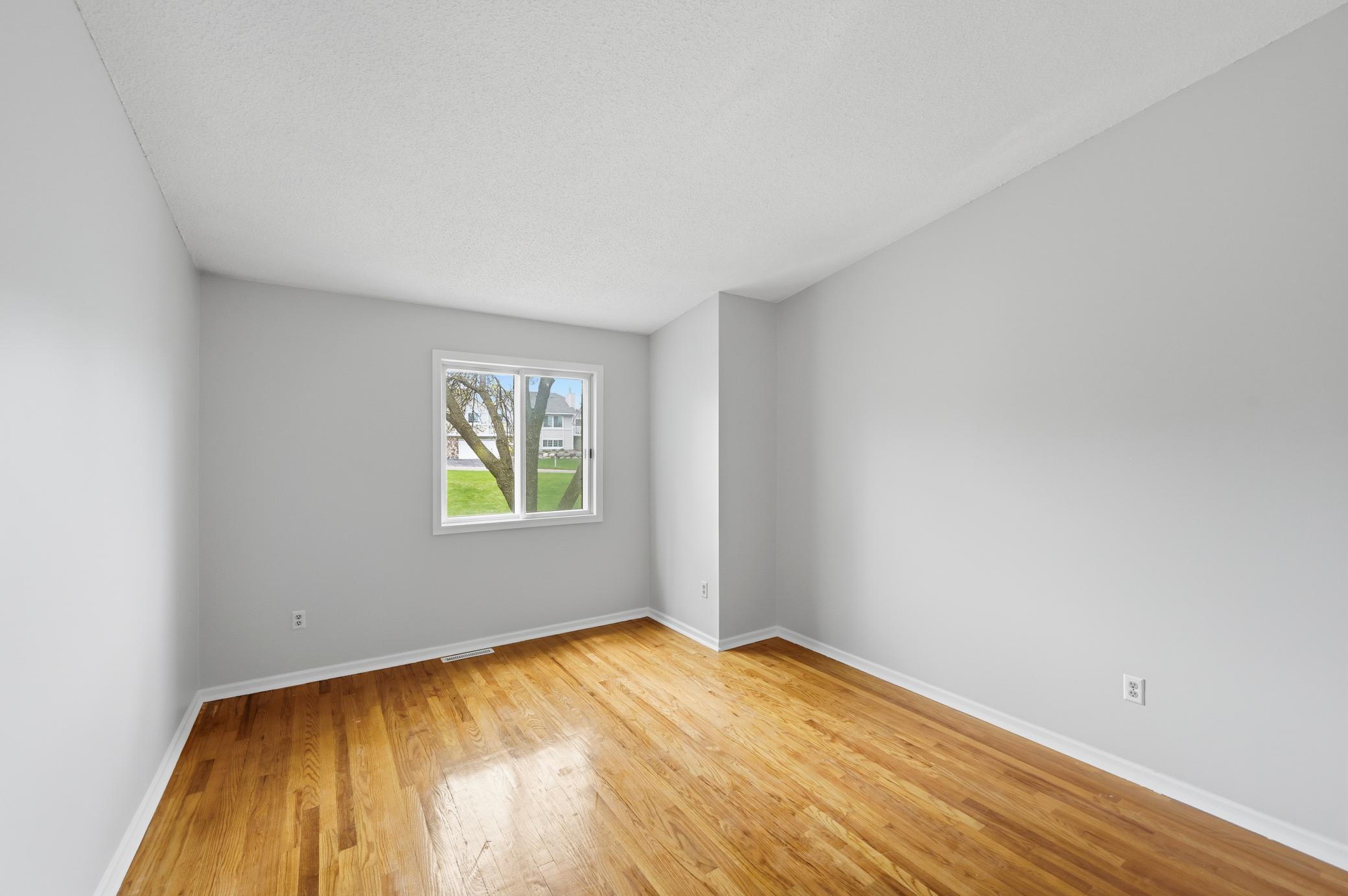 Large primary bedroom with hardwood floors and vaulted ceiling.