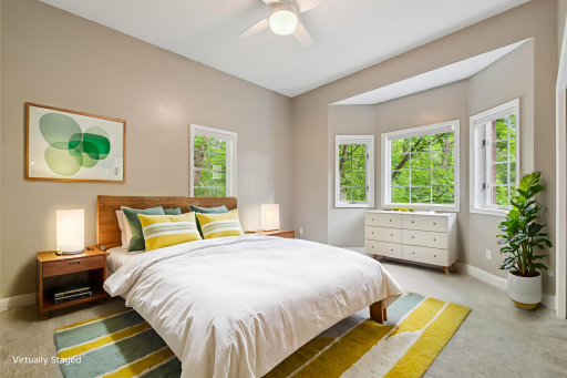 The second bedroom features a bay window that overlooks the serene front yard and lush natural green space.