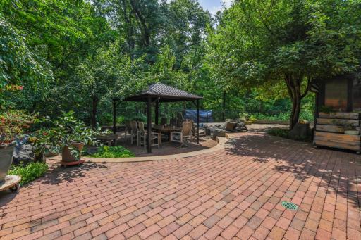 Step outside to the expansive patio and be greeted by the soothing sounds of nature. This outdoor haven features a variety of fruit trees, an impressive water feature, a dining area beneath a covered pergola, and a cozy firepit!