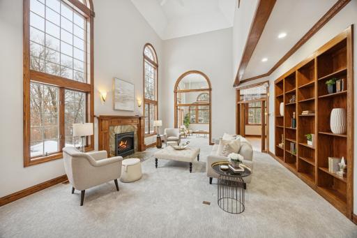 The living room is the heart of the home, featuring a dramatic two-story tray ceiling, sun-filled windows, a fireplace, and built-in bookshelves.