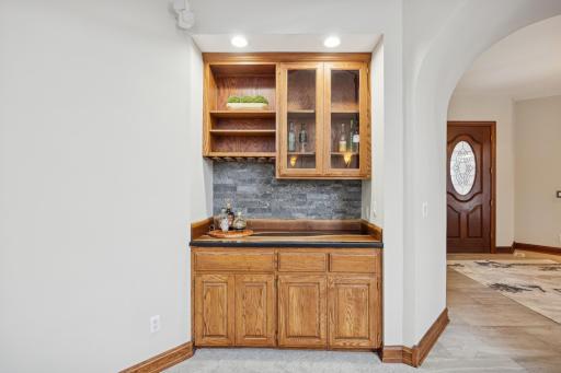 The custom-built bar features a live-edge epoxy countertop, under-cabinet lighting, and a wet bar rough-in, combining style and convenience for entertaining.
