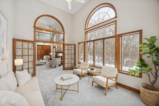 Elegant French doors and arched windows brighten and open up the space, creating an inviting and airy atmosphere..