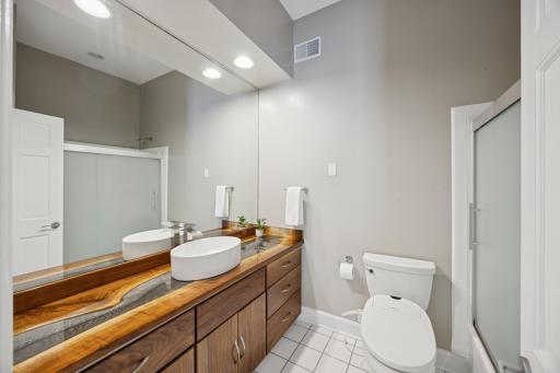 The second-level full bathroom features a gorgeous custom-built "river" epoxy countertop, Walnut cabinets, above-counter sink and wall-to-wall mirror!