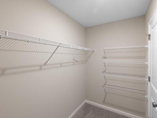 Primary Suite Walk In Closet. Photo taken of another home with similar plan and finishes. Photos and renderings may not depict actual plan, materials, & finishes may vary. All measurements are approximate.
