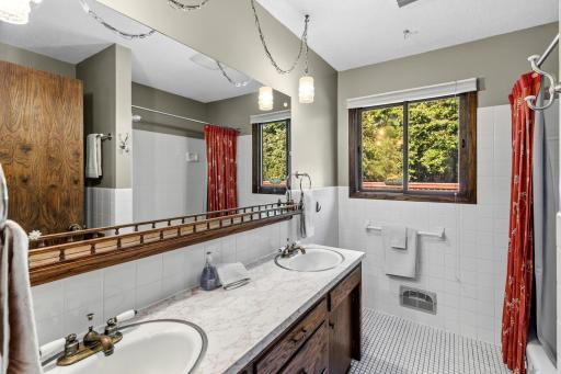 Main level full bath with tile floors and a double sink.