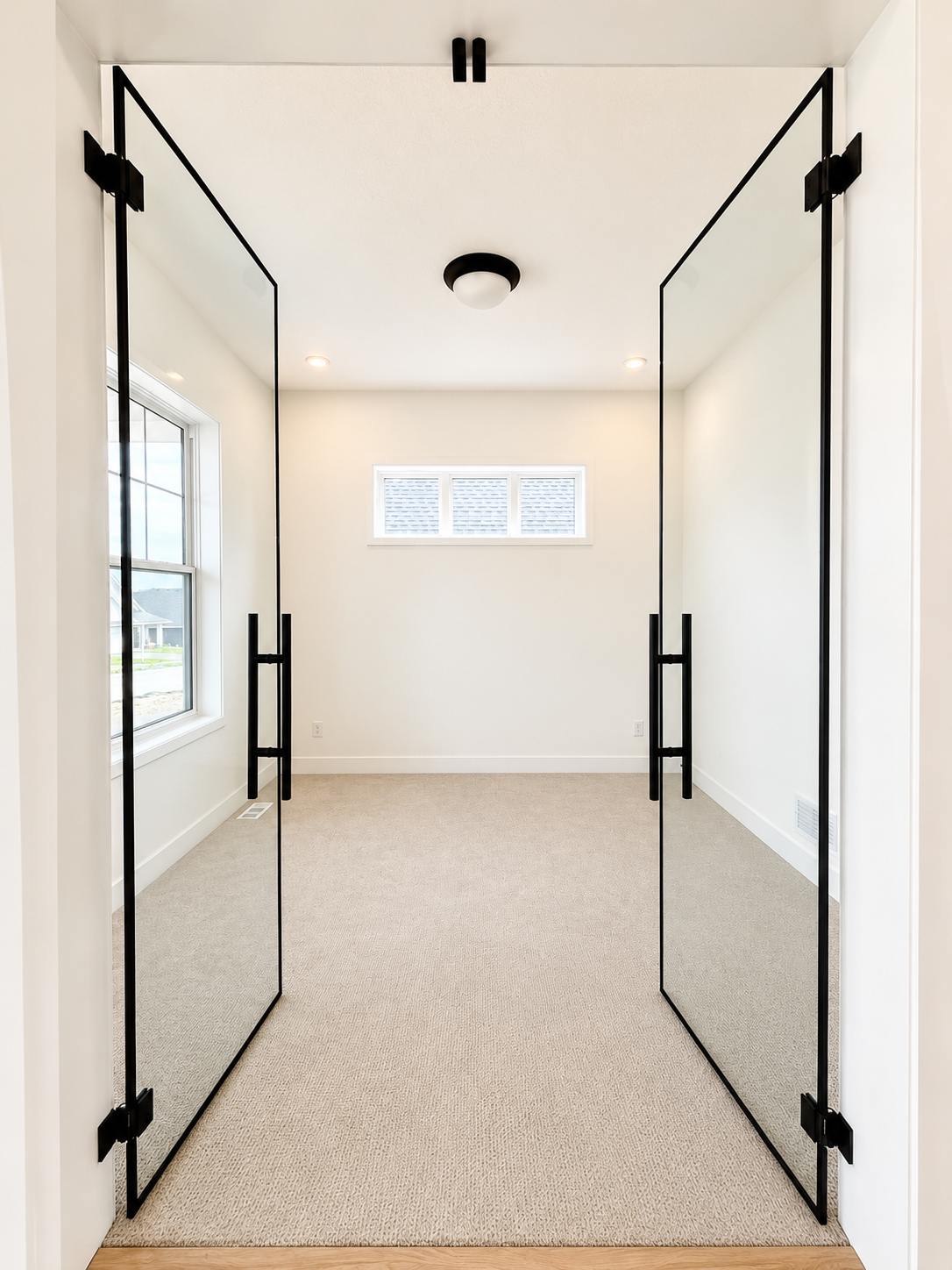 Private home office featuring striking full-glass French doors with matte black hardware, creating a bright and sophisticated workspace.