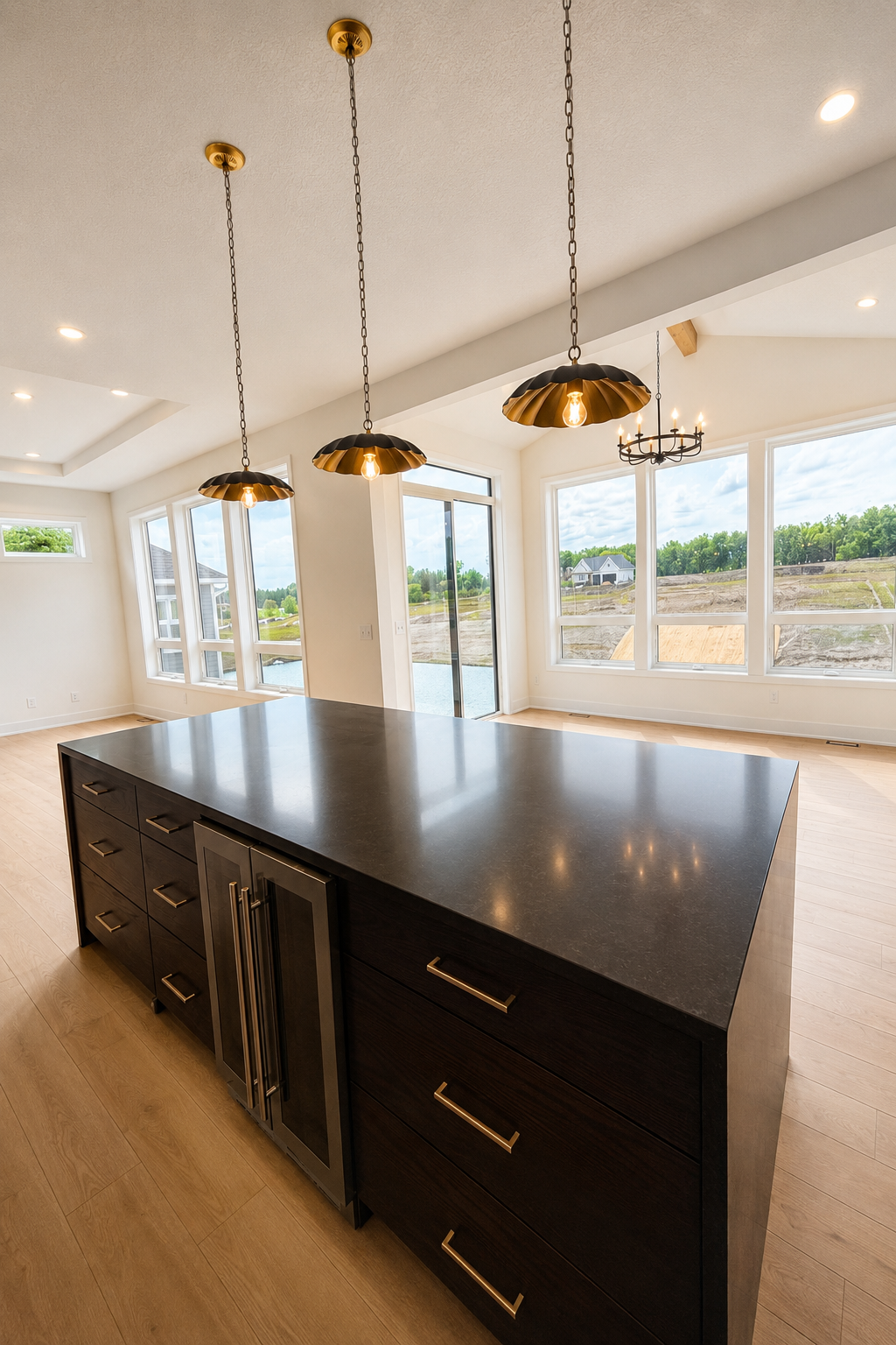 Designer kitchen showcasing an oversized center island with abundant storage, beverage refrigerator, and stylish statement pendant lighting.