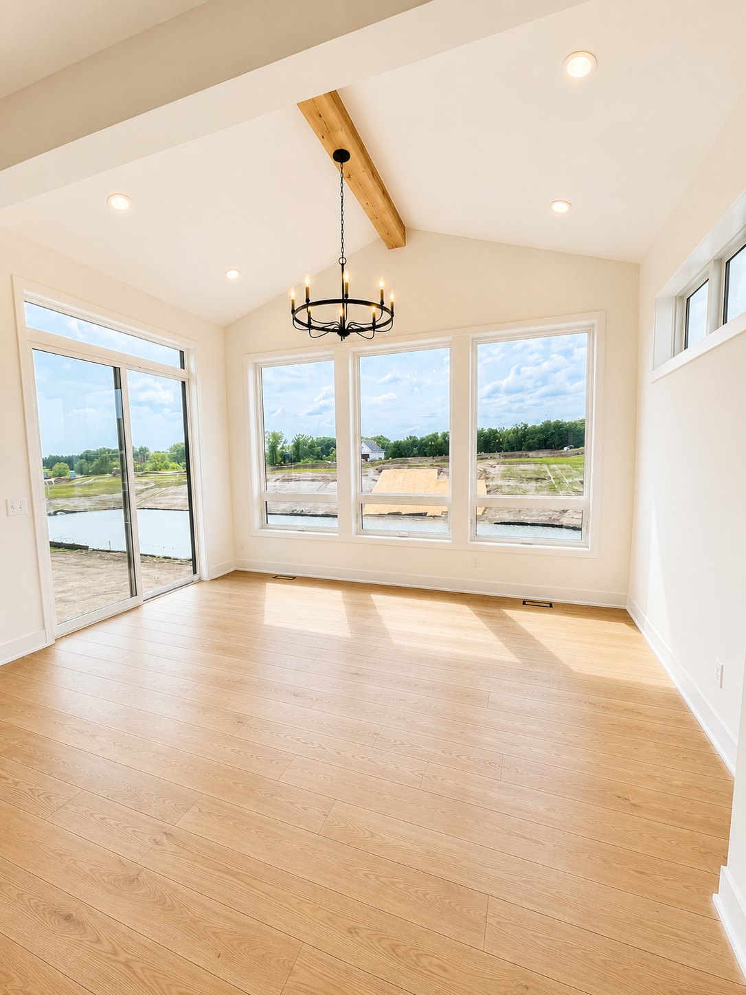 Spacious dining area surrounded by oversized windows and anchored by a dramatic chandelier, offering beautiful natural light and backyard views.