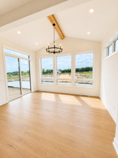 Spacious dining area surrounded by oversized windows and anchored by a dramatic chandelier, offering beautiful natural light and backyard views.