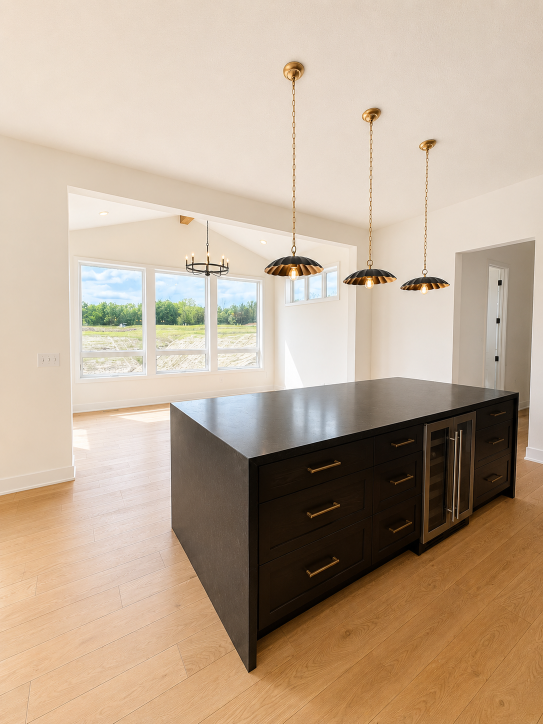 Designer kitchen showcasing an oversized center island with abundant storage, beverage refrigerator, and stylish statement pendant lighting.