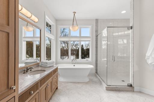 Primary bathroom with rift cut white oak custom cabinetry, soaking tub, and walk in shower.