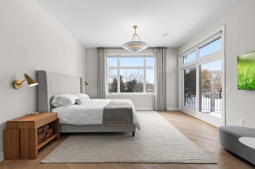 Primary bedroom with incredible light, white oak floors, and custom motorized window treatments.