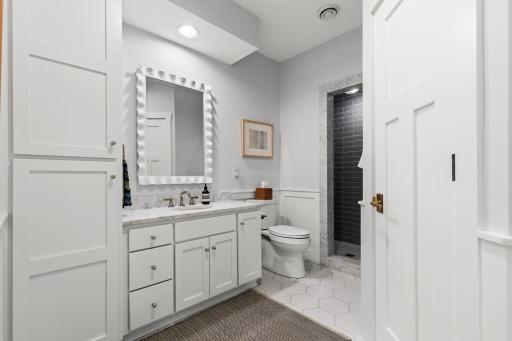 Lower level guest bathroom with Carrera marble accents, enameled vanity, new sink, and new tile.