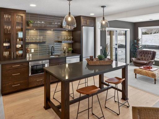 Luxurious Lower Level wet bar featuring custom cabinetry, lighting and backsplash