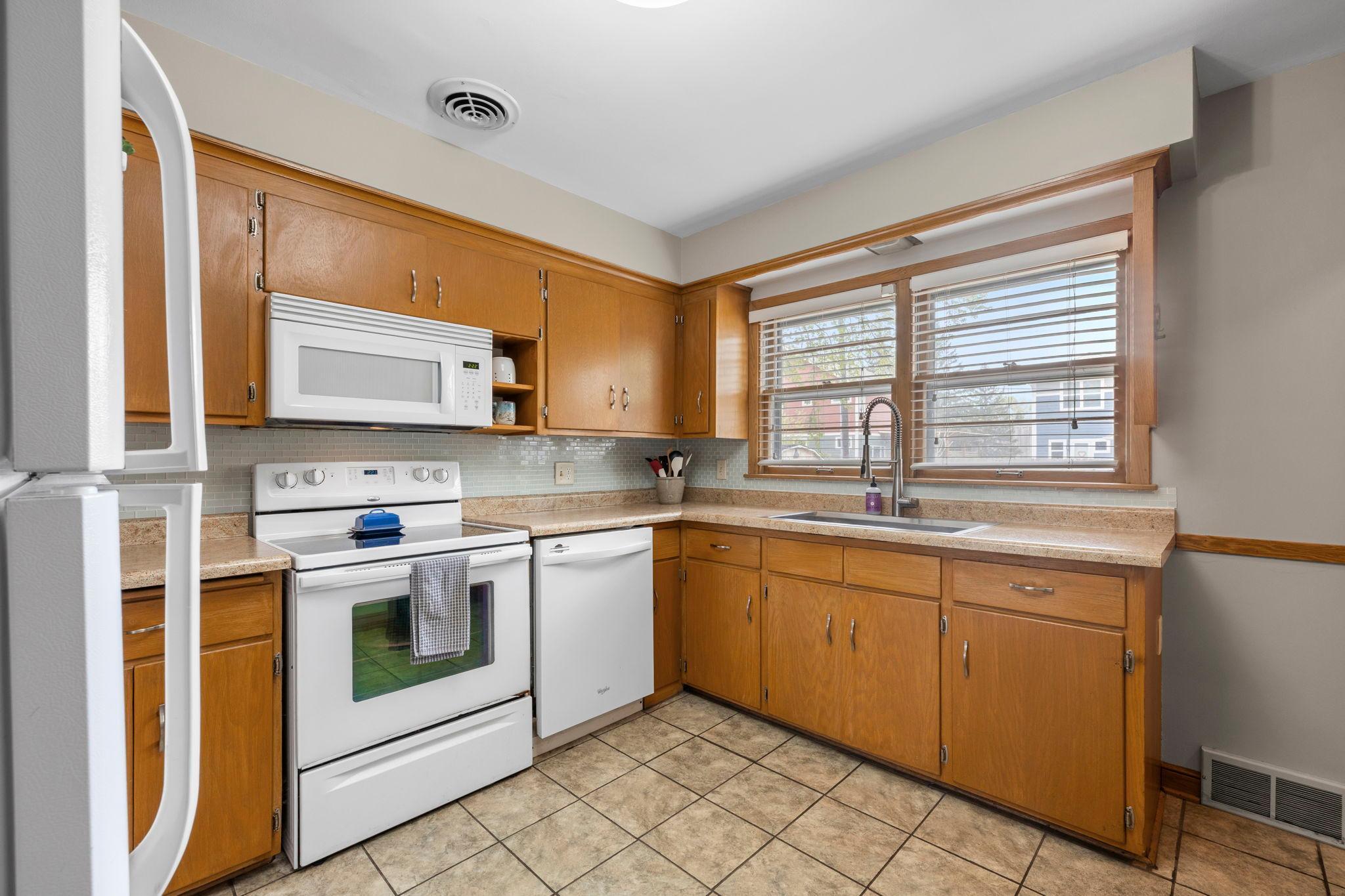 Kitchen window with backyard view. New stainless steel undermount sink, new faucet, and freshly painted kitchen