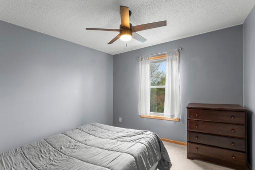 Bedroom #2 of three upstairs. Ceiling fan and view of the nature area behind.