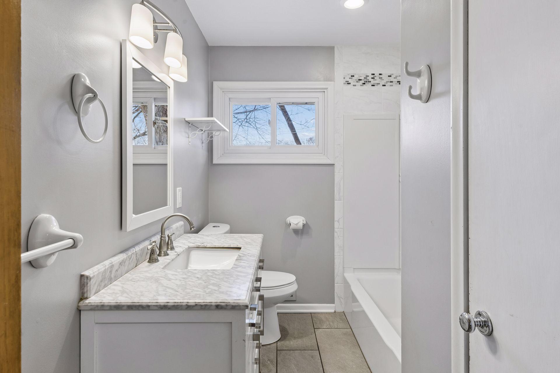 The main floor full bathroom is gorgeous with newer cabinetry, flooring, and a linen closet.
