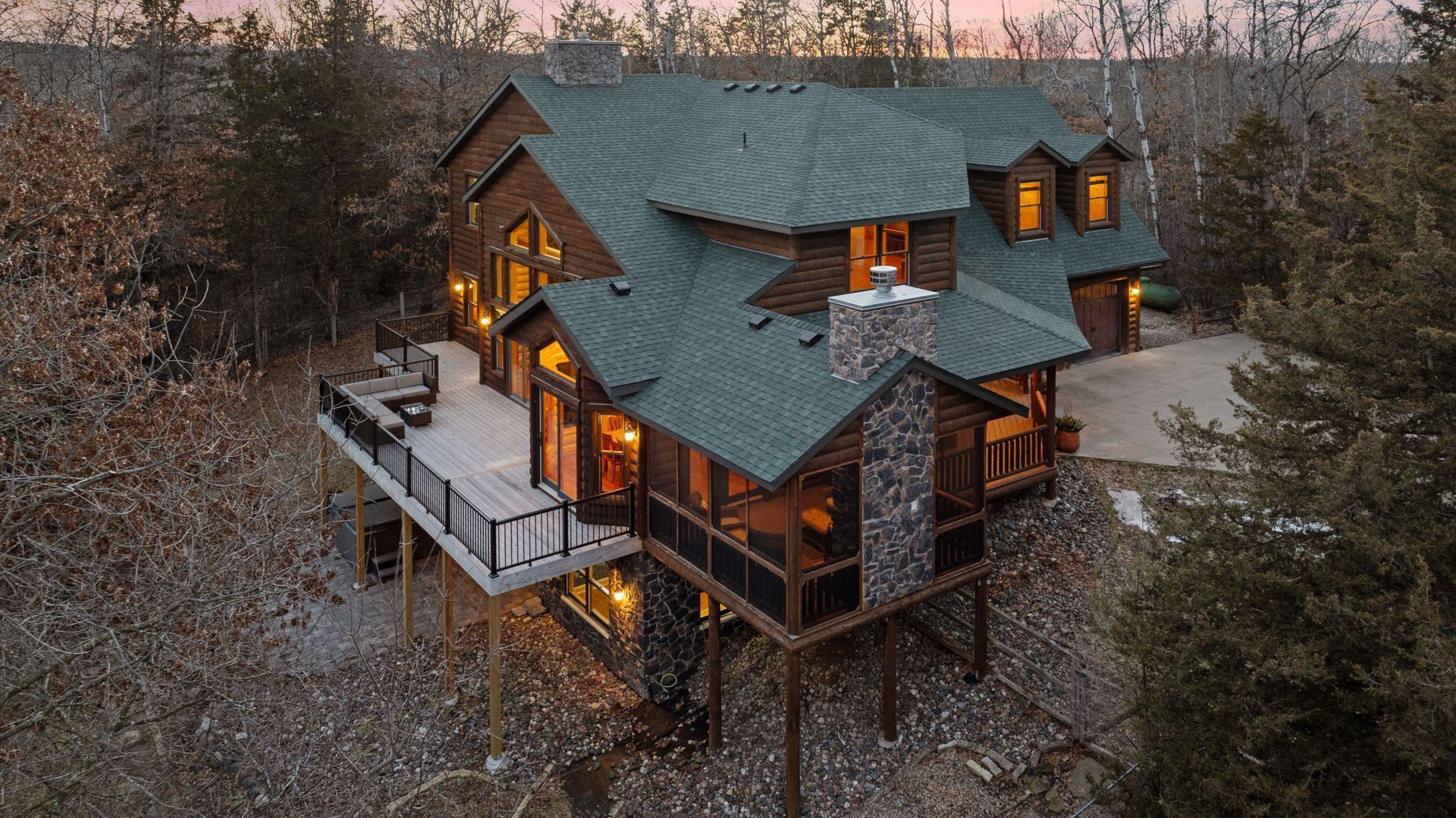 Stunning rear elevation at dusk showcasing expansive deck, walkout lower level, and amazing 3-season screen porch.