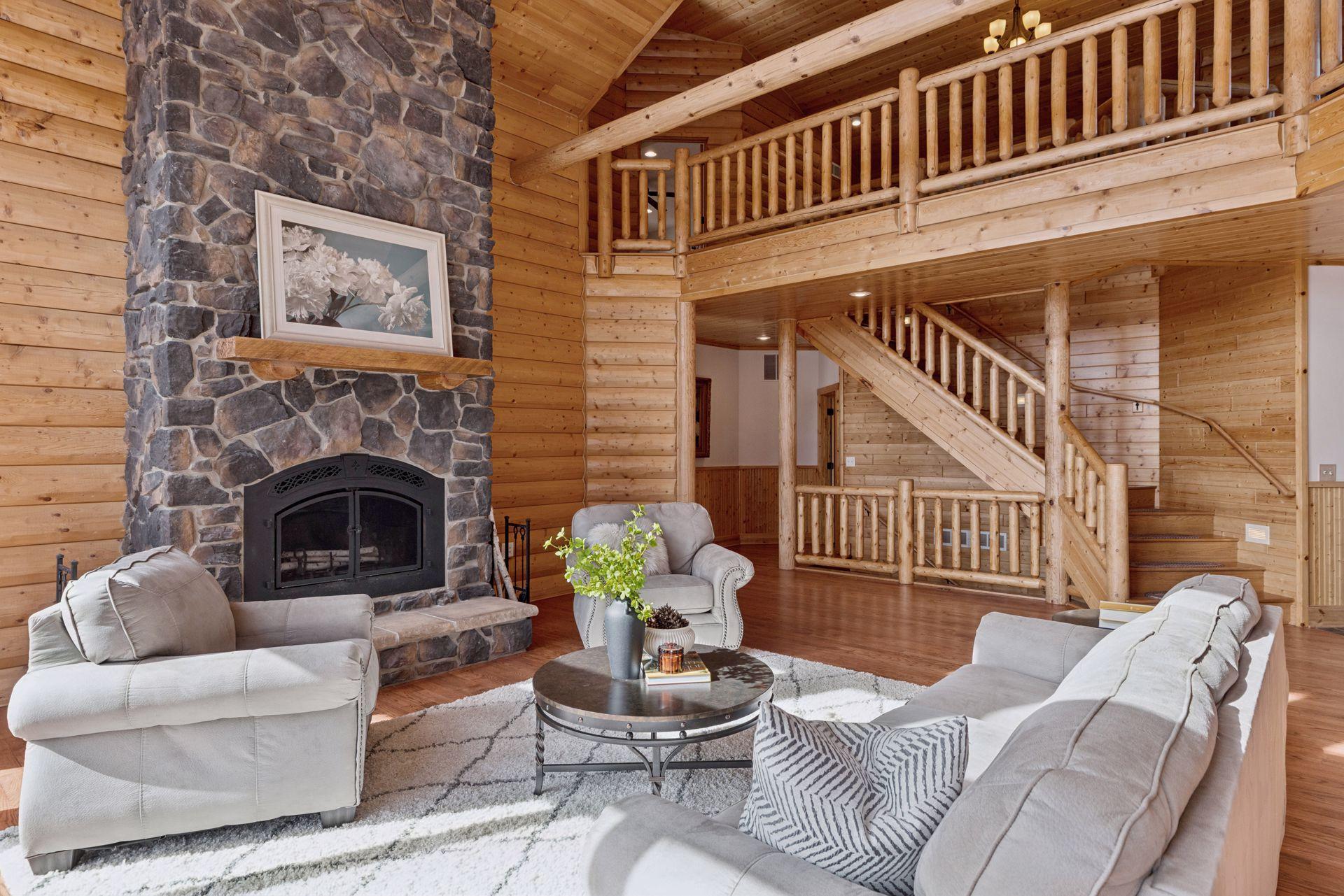 Open-concept great room featuring rustic log details and impressive stone fireplace