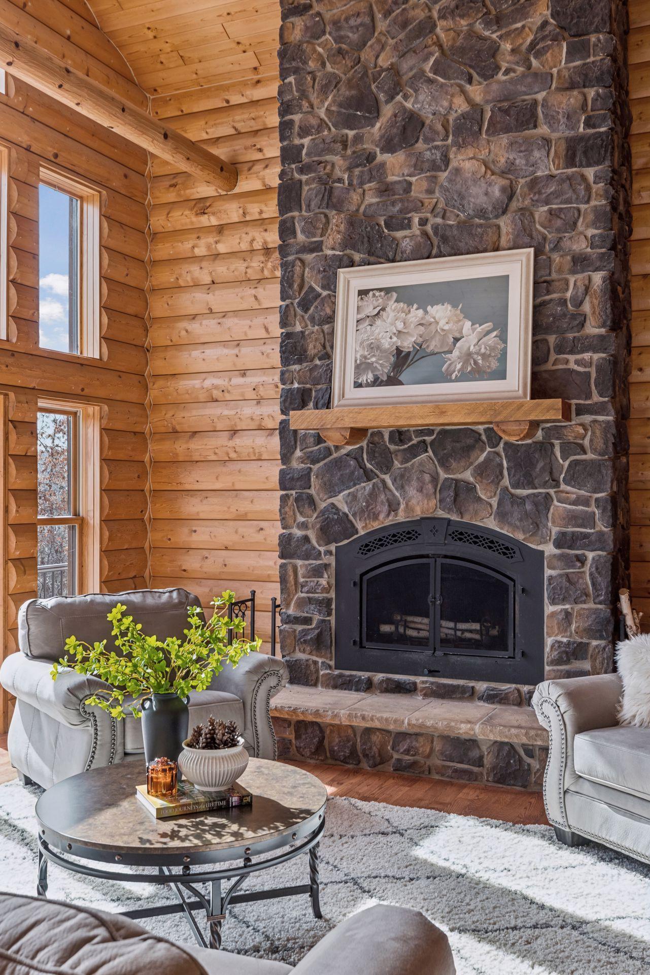 Open-concept great room featuring rustic log details and impressive stone fireplace