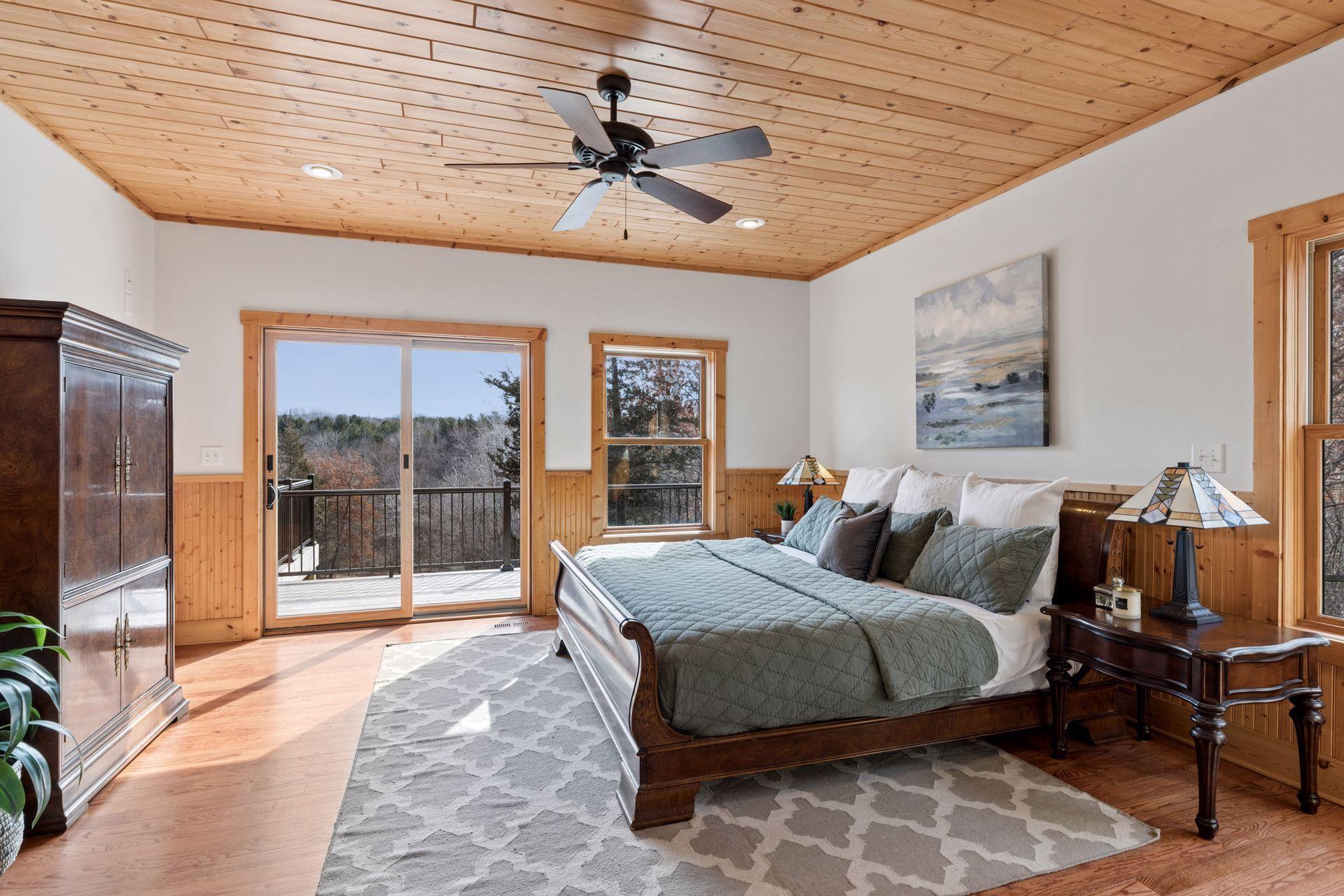 Spacious primary suite with wood ceilings, walk-in closet, private deck access, and serene wooded views