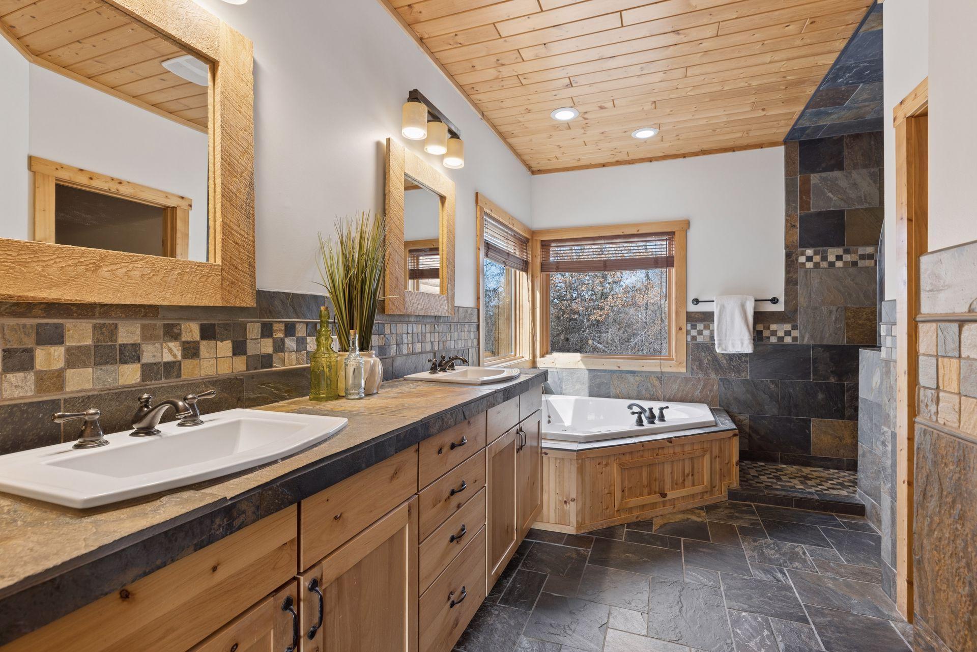 Luxurious ensuite bath with dual vanities, custom tilework, private toilet room, walk-in shower, and soaking tub