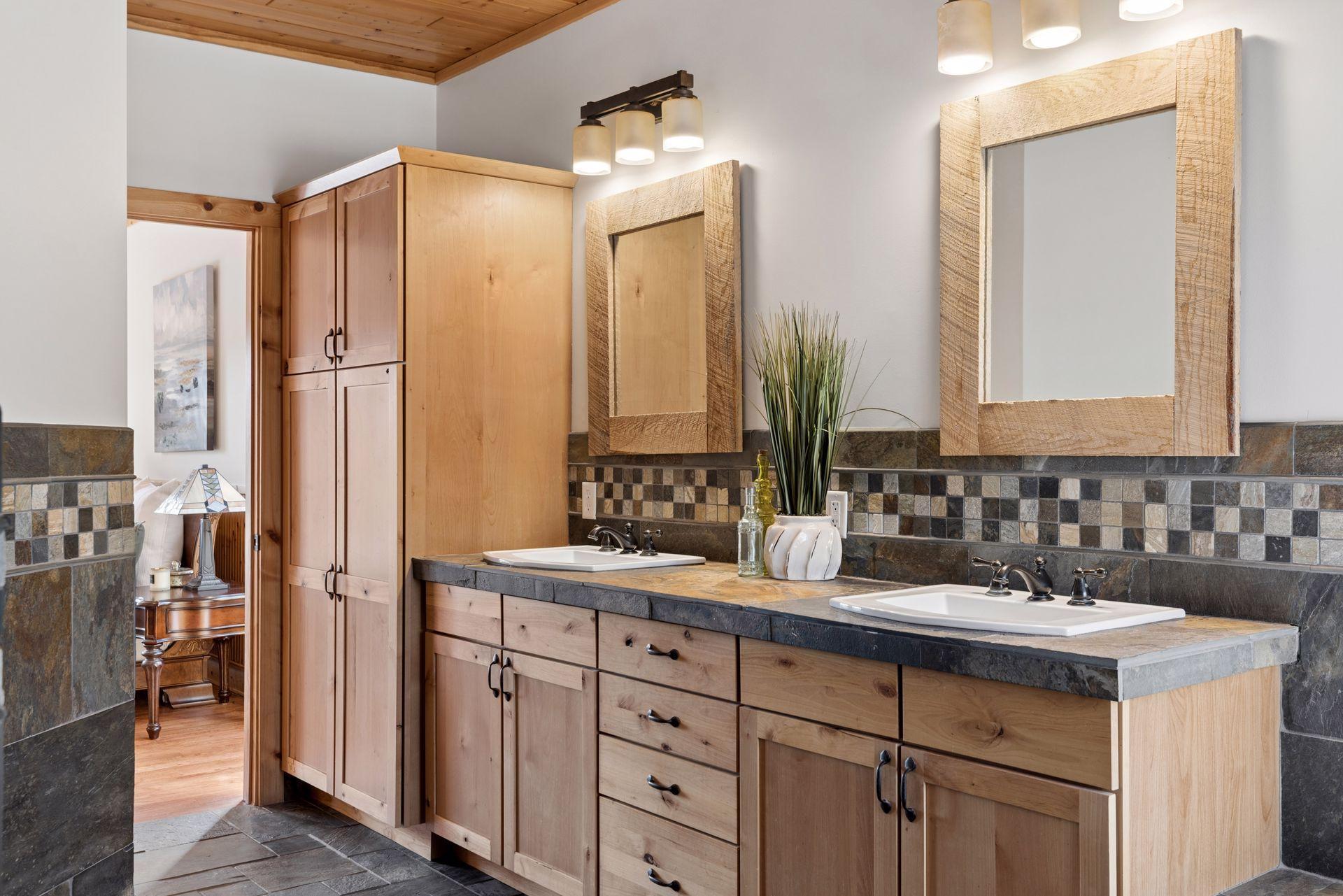 Double vanity with rustic cabinetry, stone countertops, and ample storage