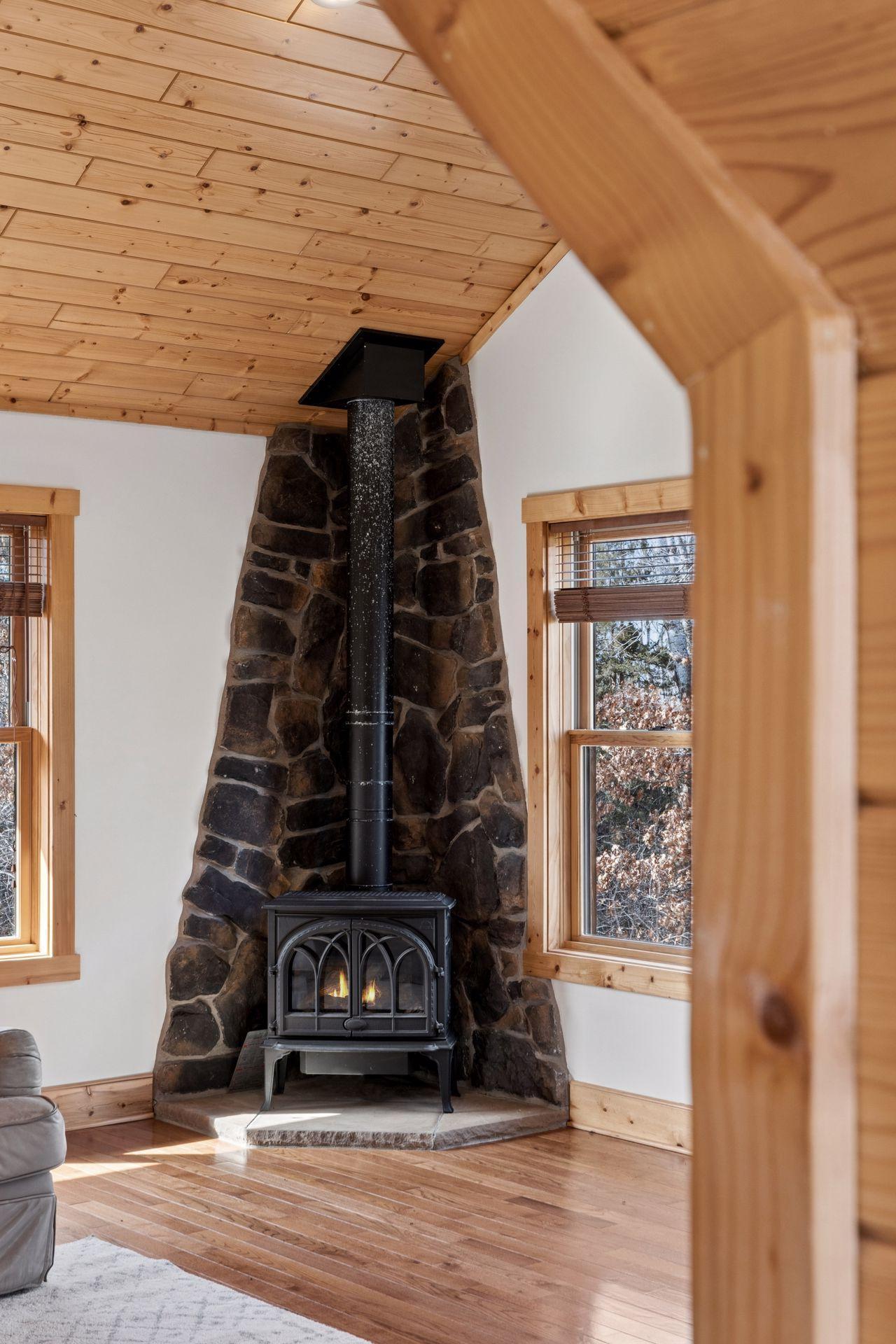 Inviting loft living area featuring stone surround wood stove and warm finishes