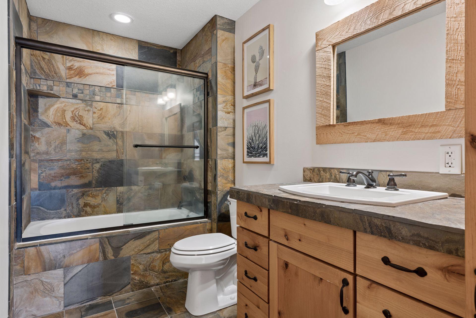 Well-appointed upper-level full bath with custom tile surround, rustic finishes, and ample storage